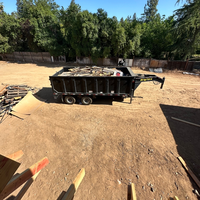 A large black dumpster filled with construction debris, such as drywall and wood scraps