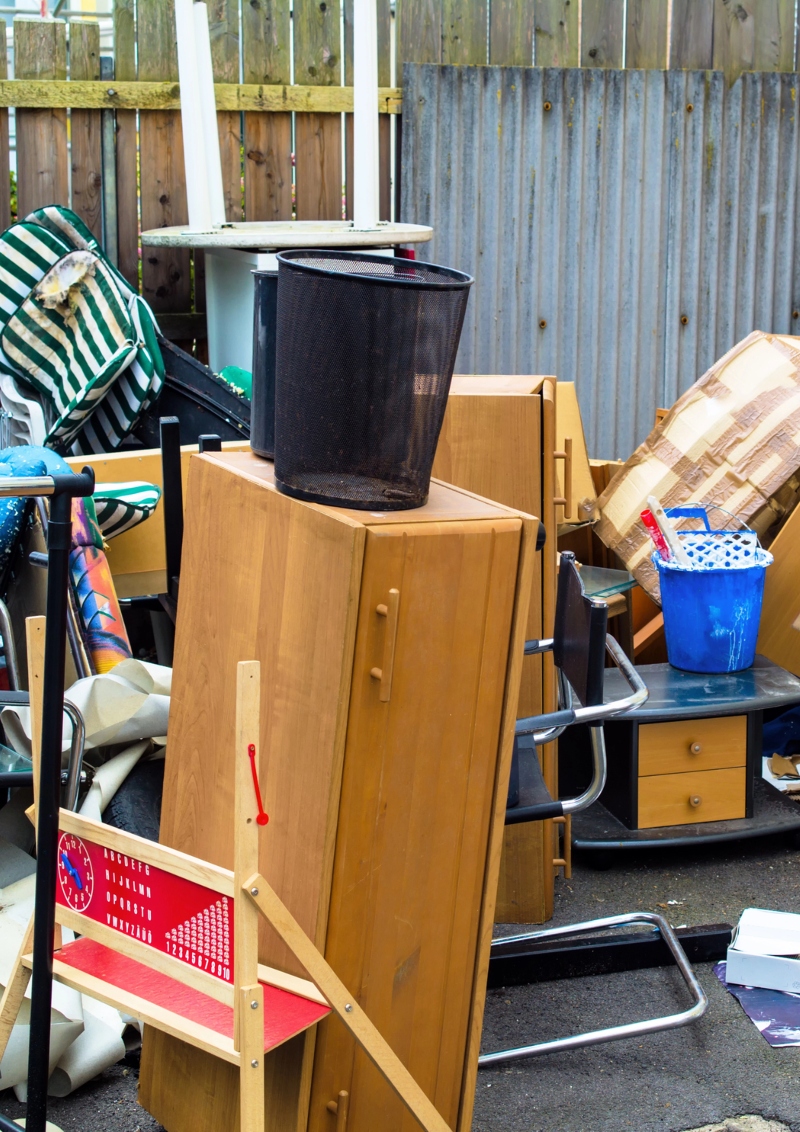 A cluttered yard with a pile of discarded furniture and household items, waiting for removal