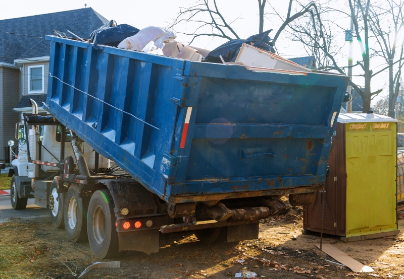 A dumpster being filled with trash from a construction site